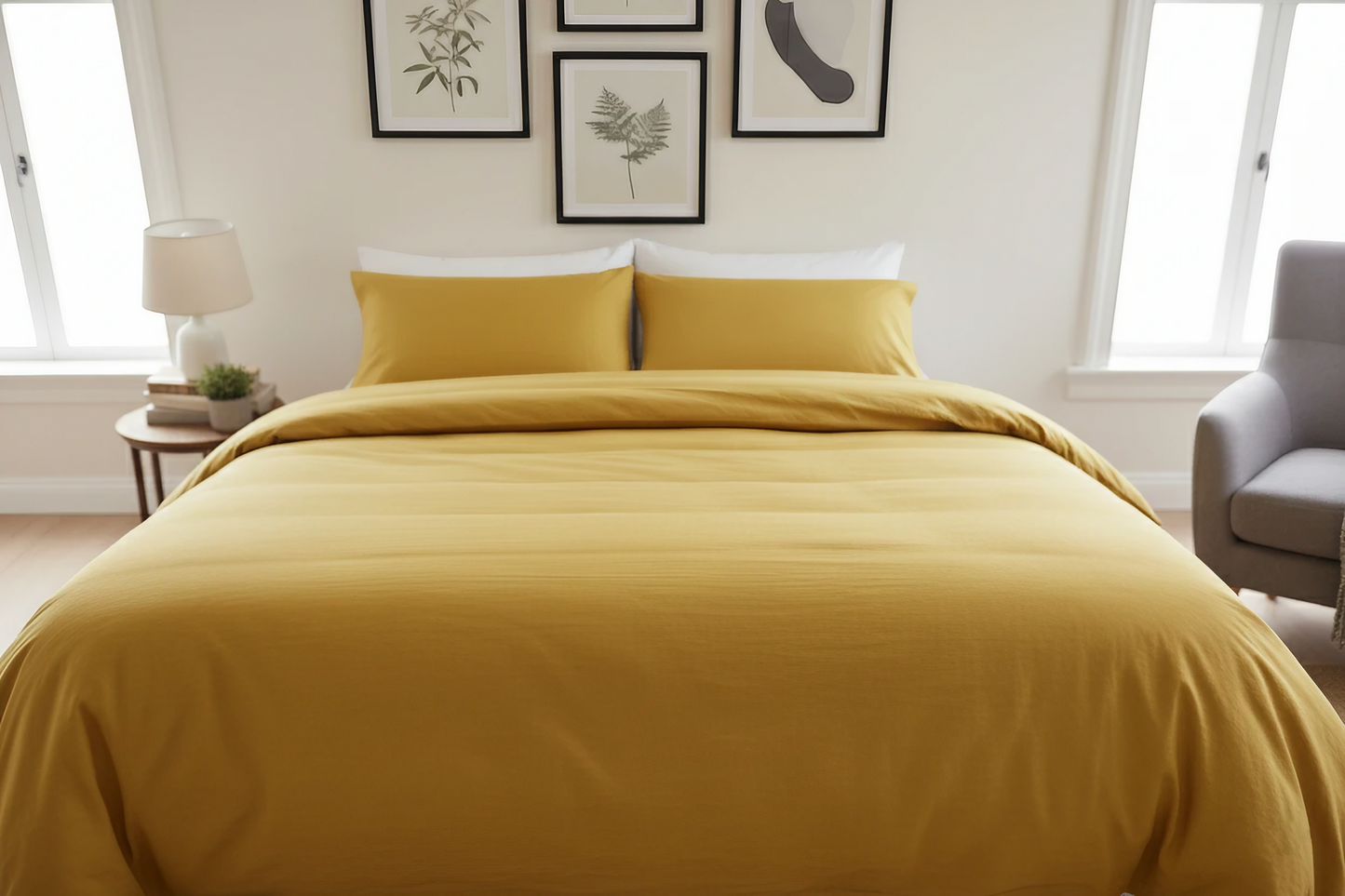Yellow bedspread on a bed in a well-lit bedroom with framed art on the wall.