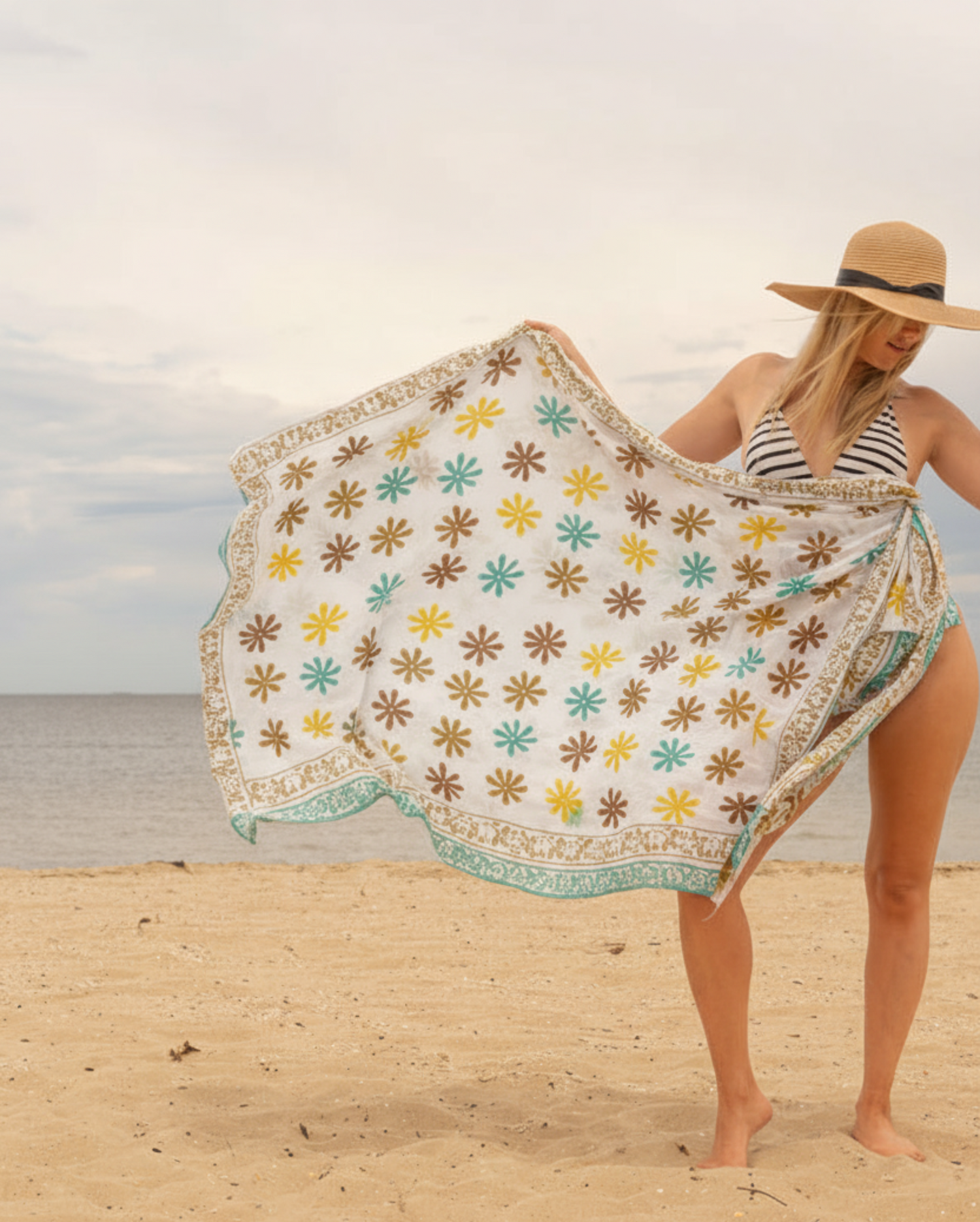 Woman on a beach holding a floral-patterned towel