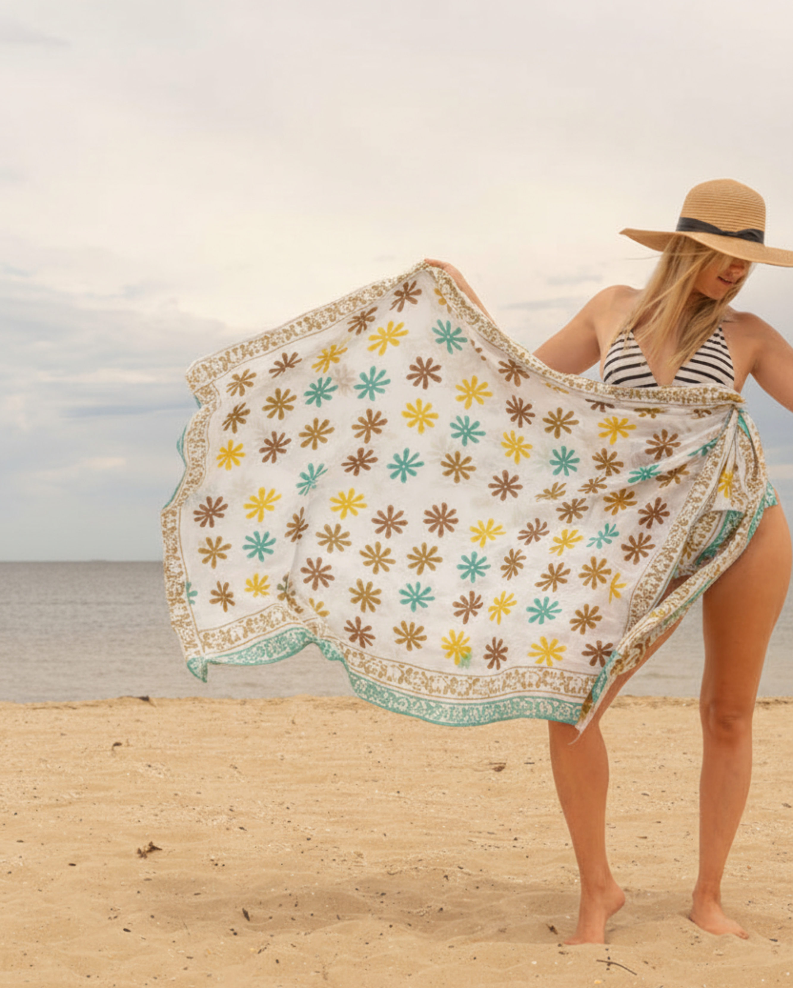 Woman on a beach holding a floral-patterned towel