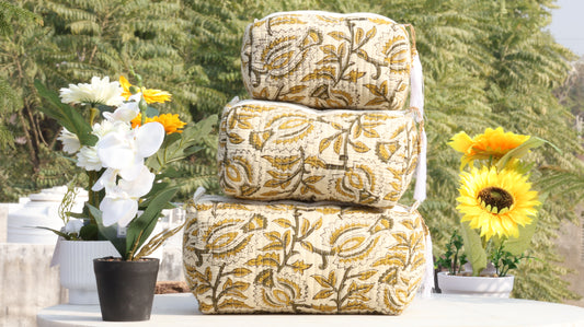 Stack of patterned cushions on a table with flowers in the background