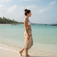 Woman walking on a beach with clear blue water and palm trees in the background