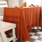 Dining table with an orange tablecloth, white chairs, and a checkered floor.