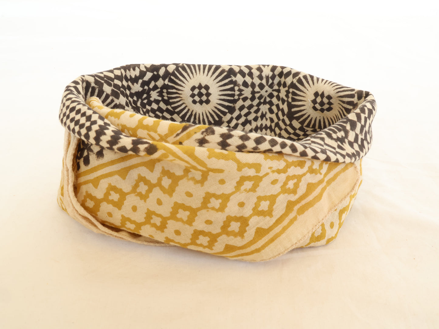 Fabric basket with black and white patterned lid on a beige background