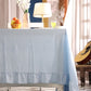 Light blue curtain with a decorative lamp and floral arrangement in the background