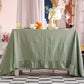 sage Green tablecloth on a wooden table with decorative items in a room with checkered floor and curtains.