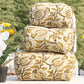 Stack of patterned cushions on a table with flowers in the background