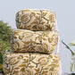 Stack of patterned fabric rolls with flowers in the background