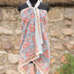 Handblock printed cotton sarong with coral floral design on blue background displayed on mannequin outdoors