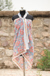 Handblock printed cotton sarong with coral floral design on blue background displayed on mannequin outdoors
