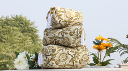 Stack of patterned pillows with flowers in the background
