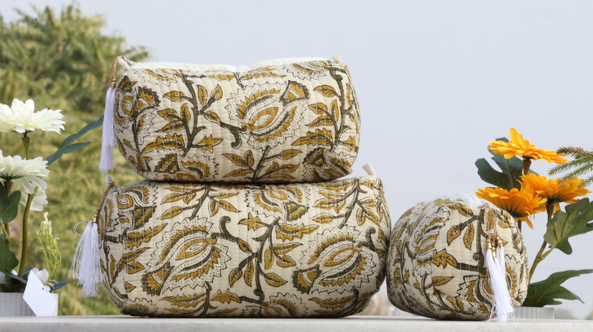 Decorative pillows with floral patterns on a white surface with flowers in the background