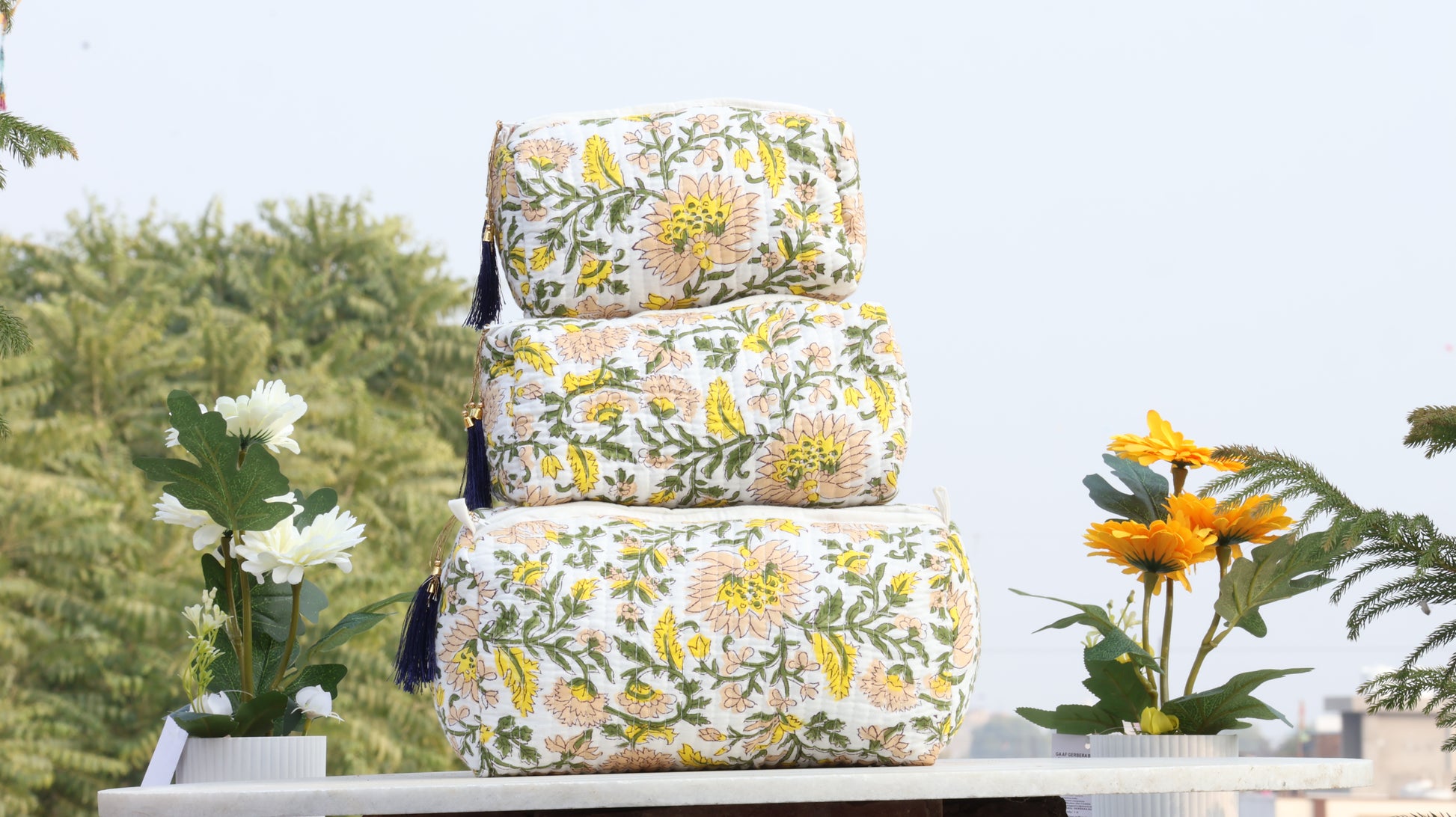 Stack of floral-patterned bags on a table with plants in the background