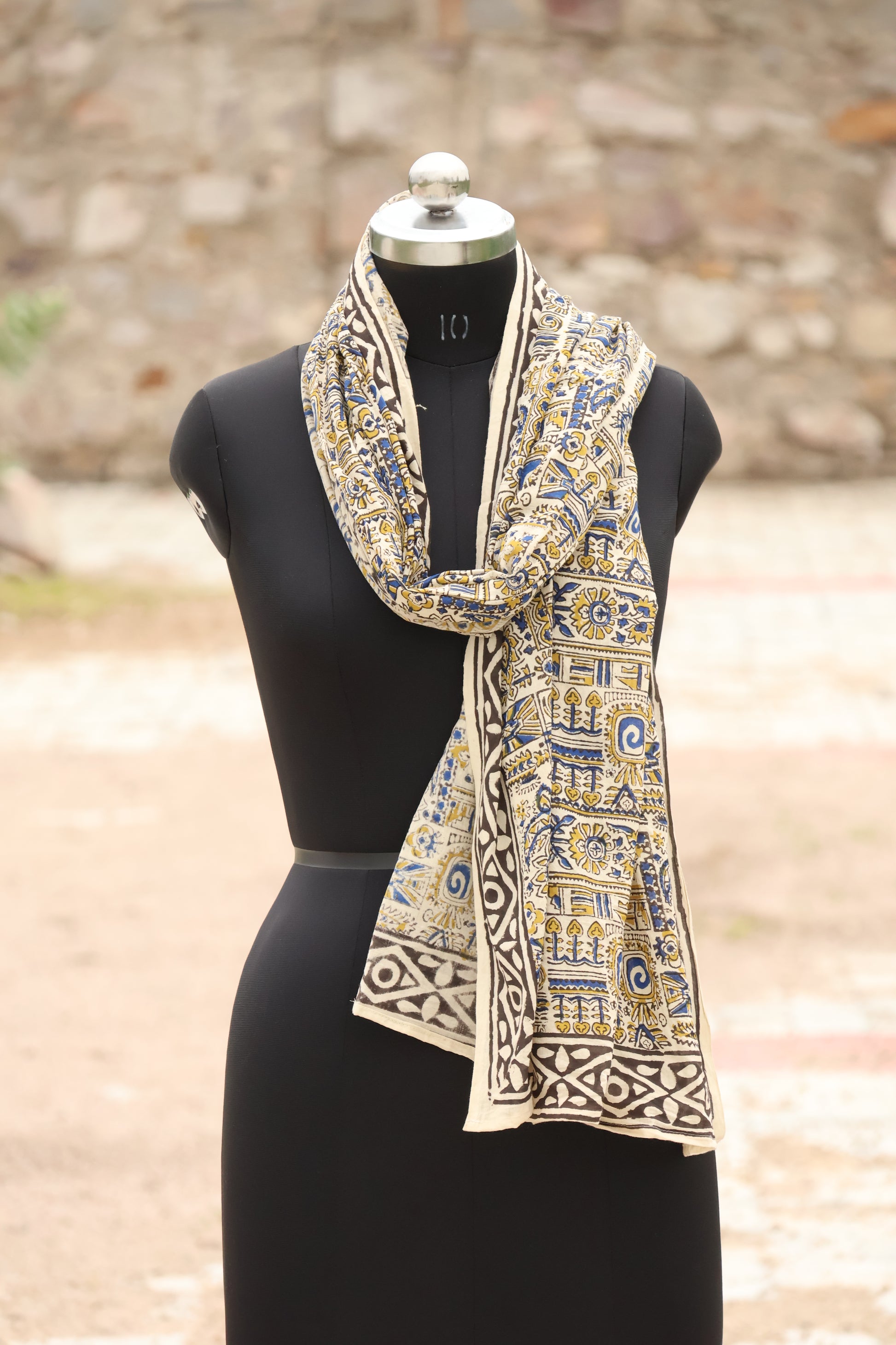 Decorative bow tie with intricate patterns on a mannequin against a blurred natural background