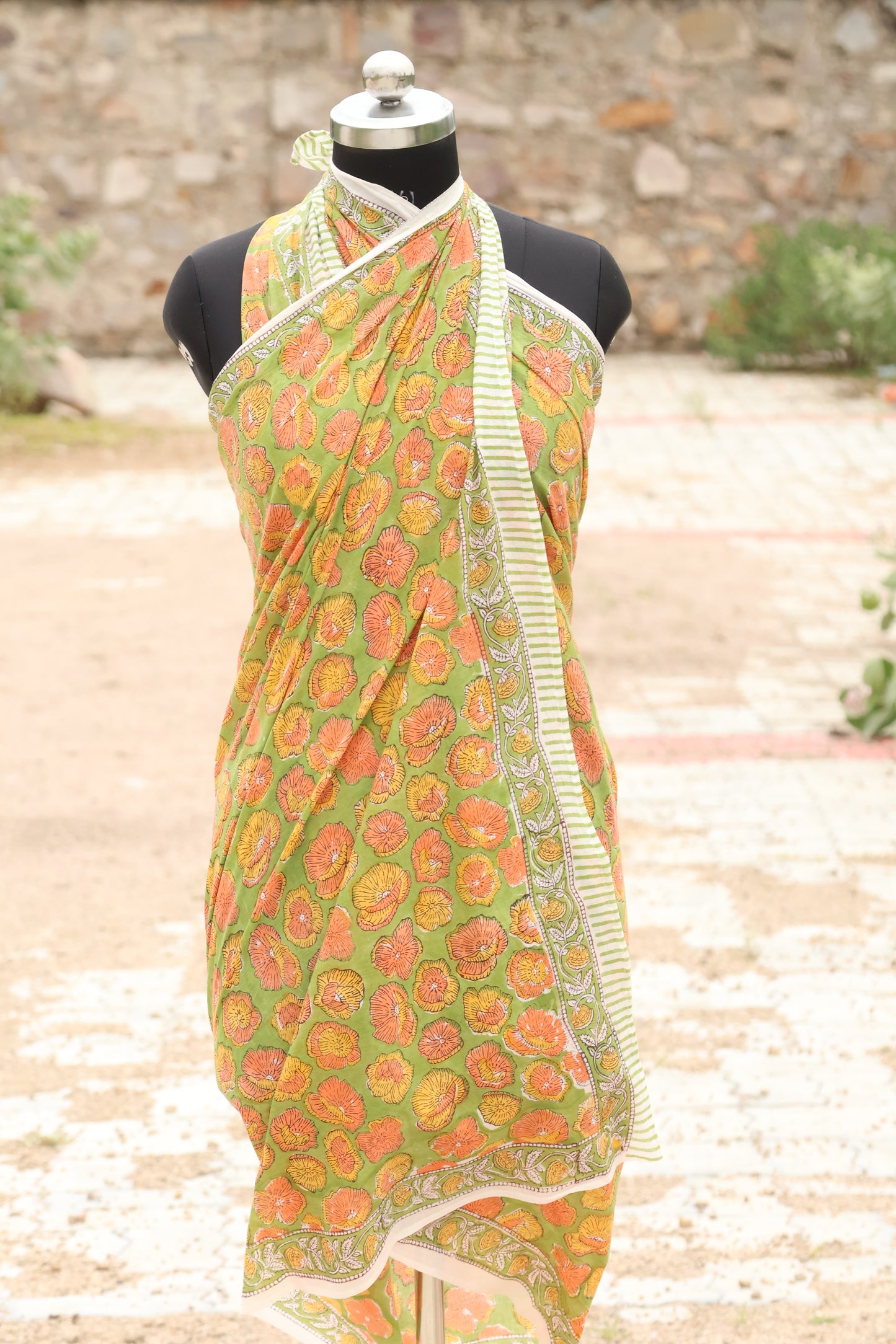 Green and orange patterned fabric on a mannequin against a blurred natural background