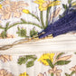 Floral-patterned pouch with a zipper and decorative brooch.