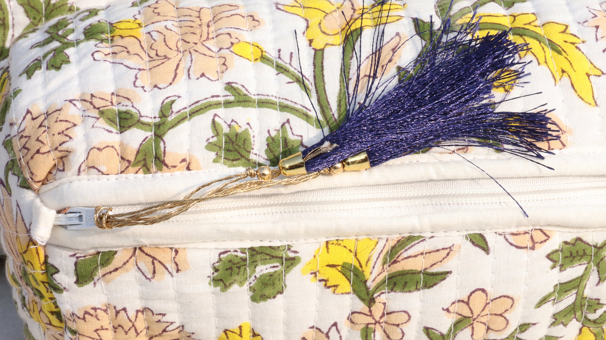 Floral-patterned pouch with a zipper and decorative brooch.