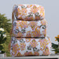 Stack of patterned fabric bags on a table with plants in the background