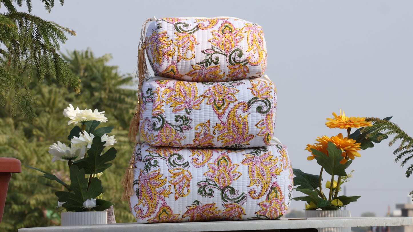 Stack of patterned fabric bags on a table with plants in the background