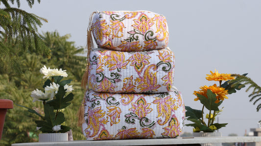 Stack of patterned fabric bags on a table with plants in the background