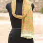 Mannequin wearing a green floral scarf with a blurred outdoor background