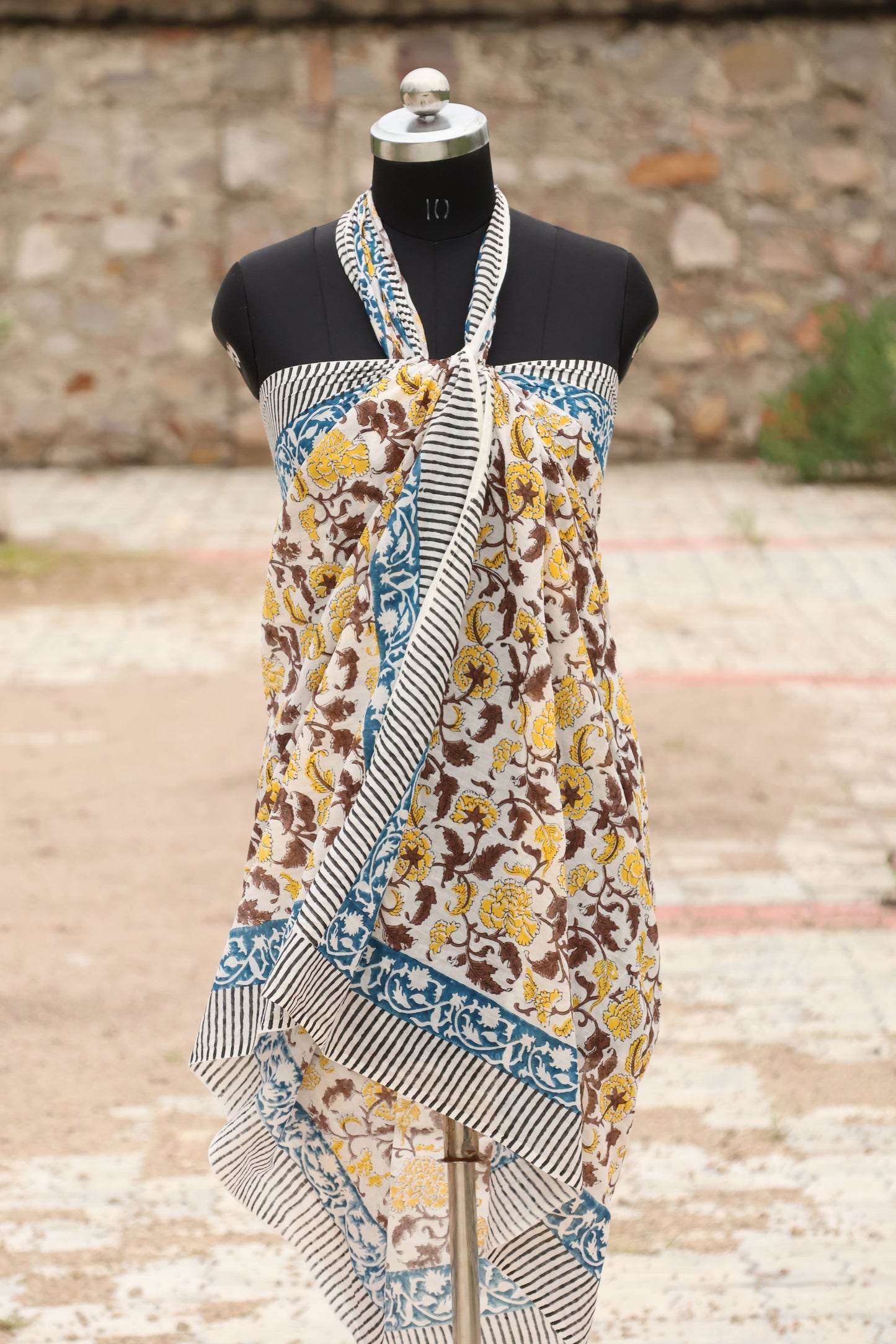 Handblock printed cotton sarong draped on a mannequin, featuring yellow floral motifs, a blue decorative border