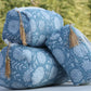 Blue quilted toiletry bag displayed outdoors with flowers on both sides