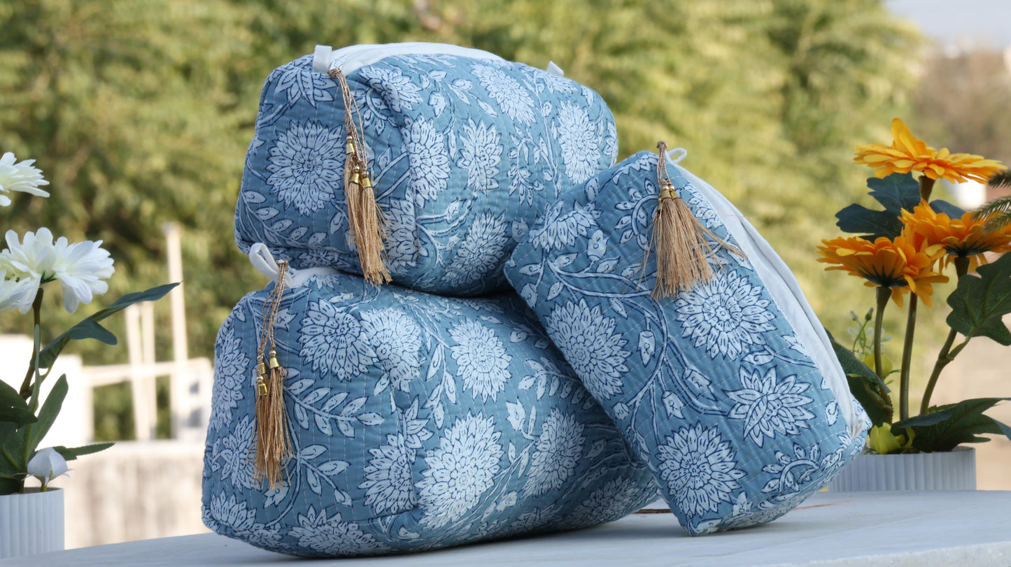 Blue quilted toiletry bag displayed outdoors with flowers on both sides