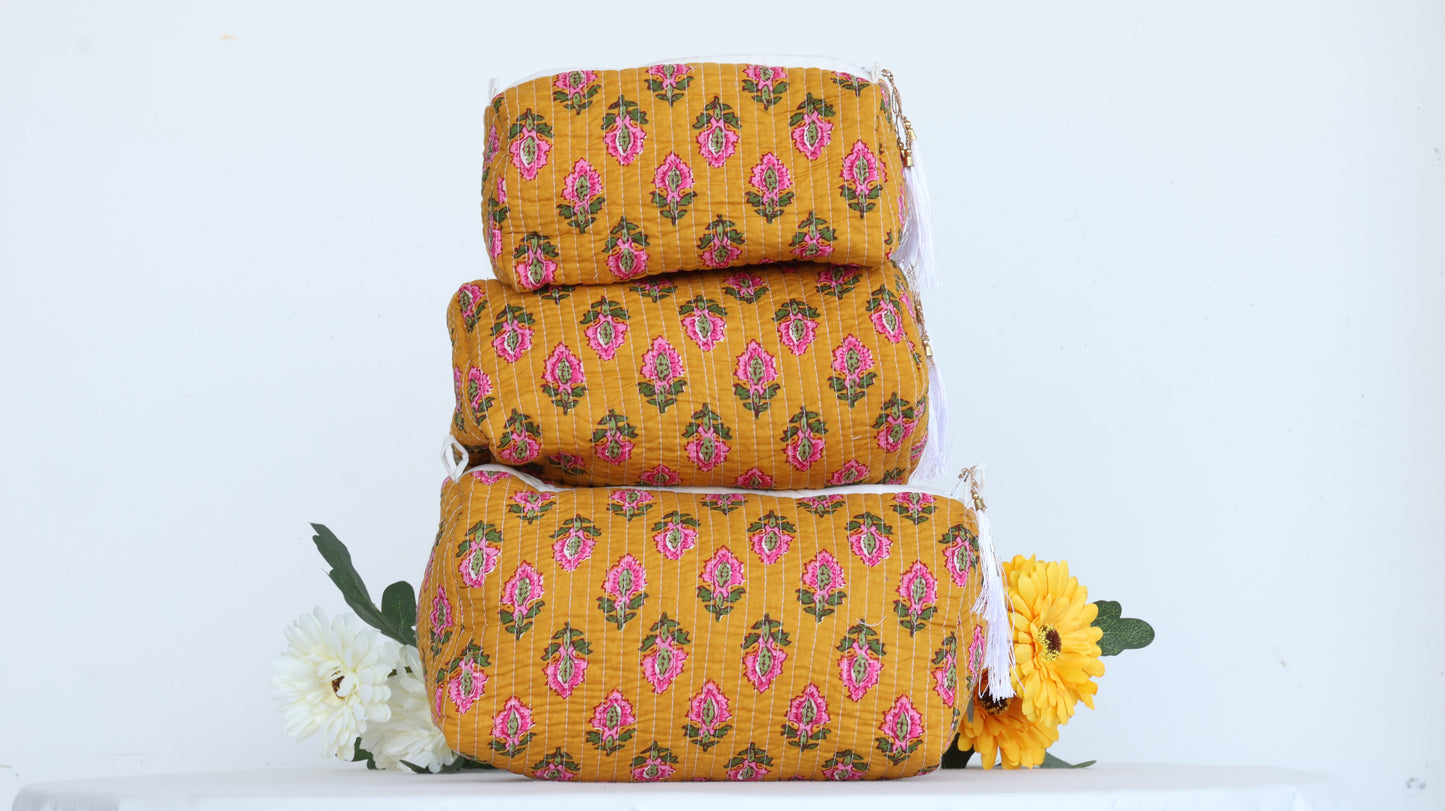 Stack of three yellow floral-patterned makeup bags with a white background