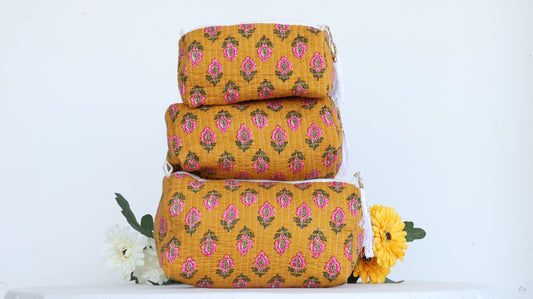 Stack of three yellow floral-patterned makeup bags with a white background