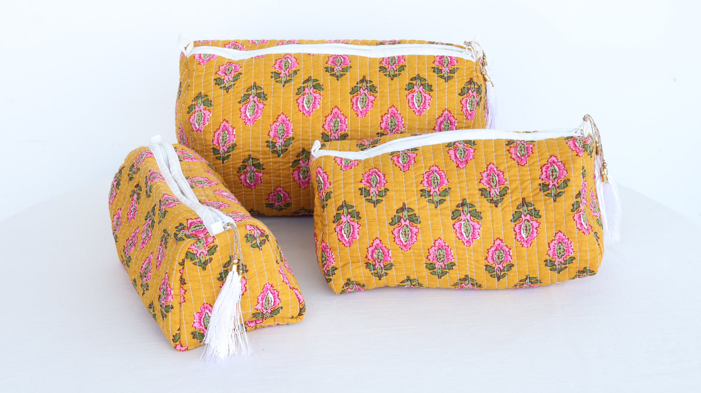 Three yellow fabric pouches with pink floral patterns on a white background