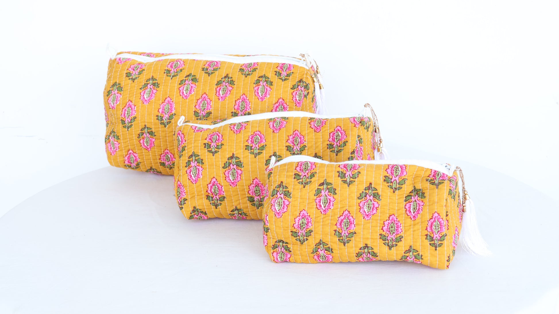 Three yellow patterned pouches on a white background