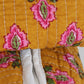 Close-up of a yellow fabric with pink and green floral patterns on a white background