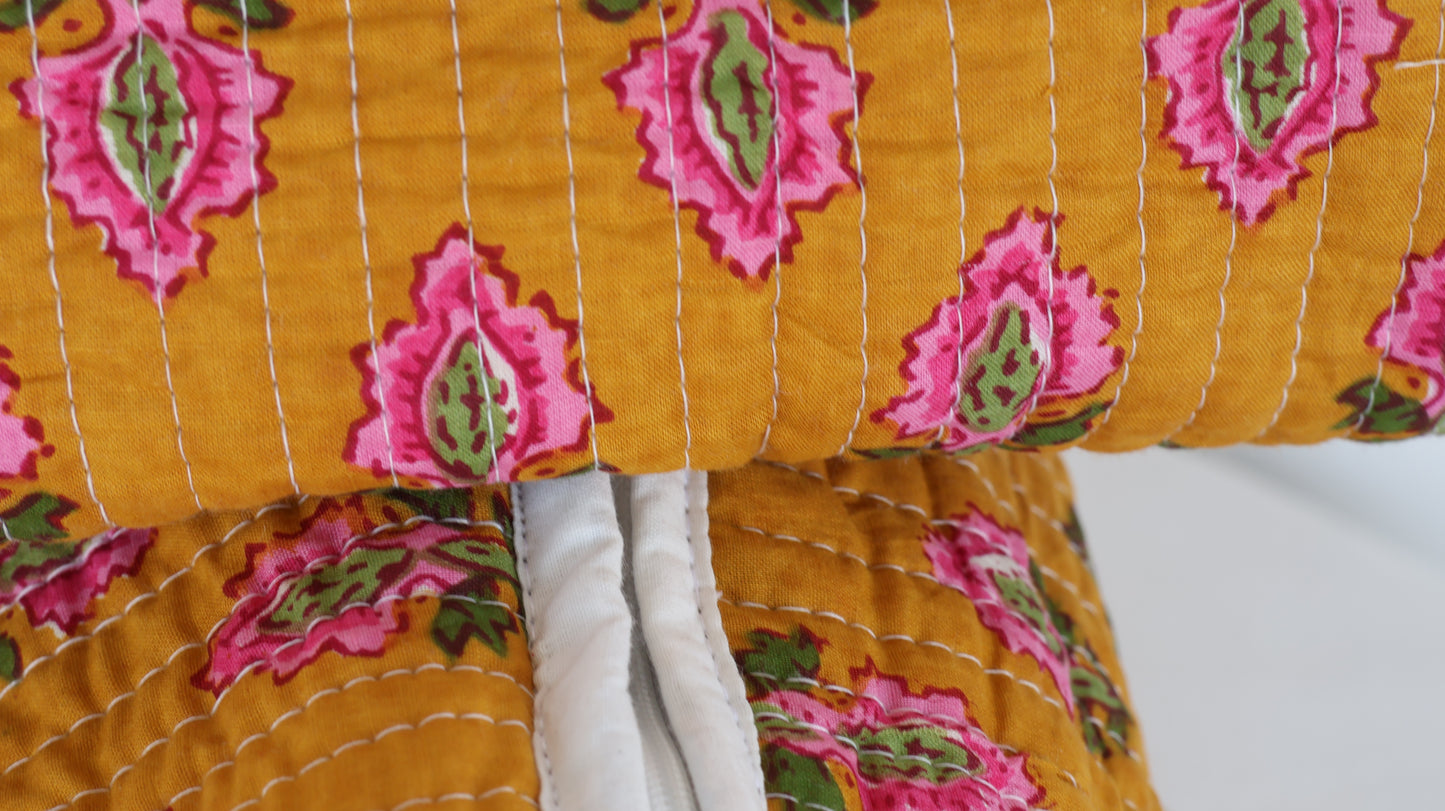 Close-up of a yellow fabric with pink and green floral patterns on a white background