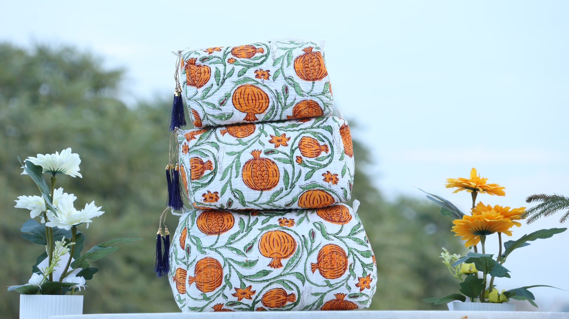 Stack of patterned fabric boxes with tassels on a blurred natural background