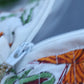 Close-up of a zipper on a fabric with colorful patterns, including green and orange elements.