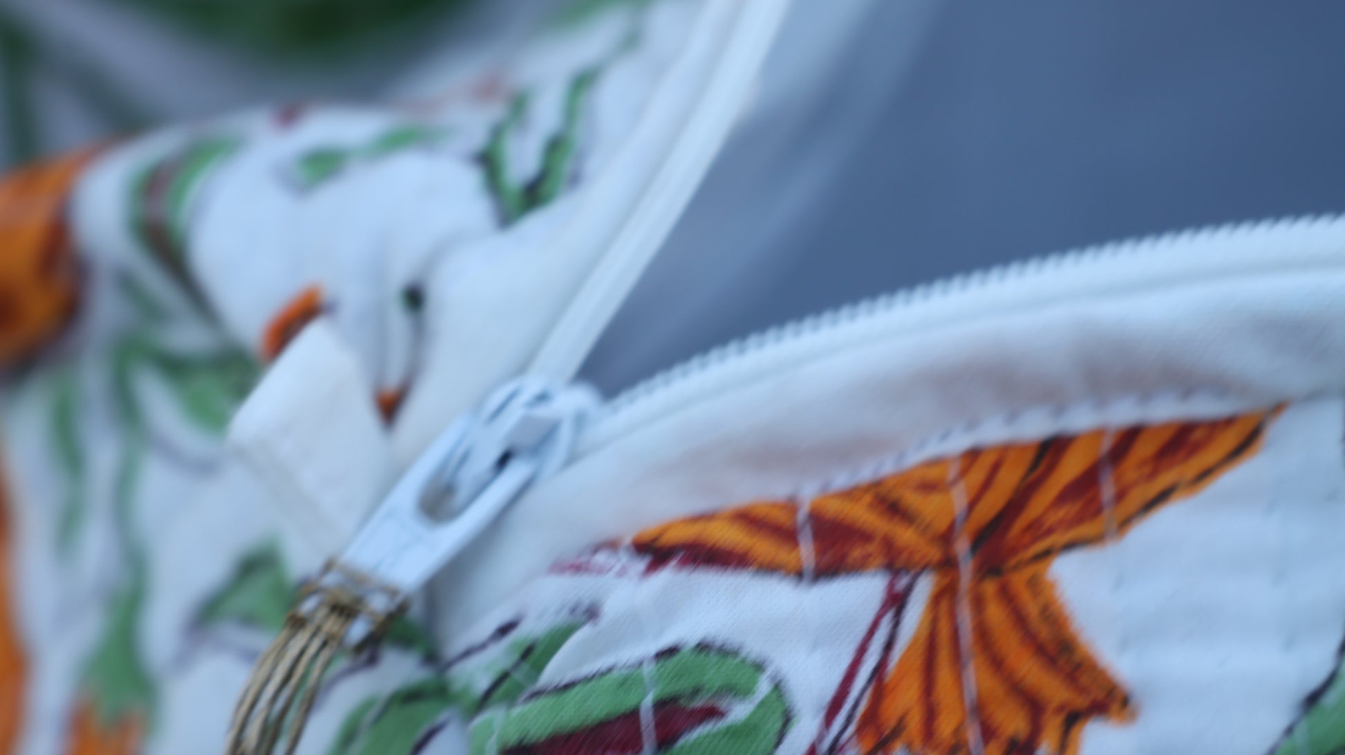 Close-up of a zipper on a fabric with colorful patterns, including green and orange elements.