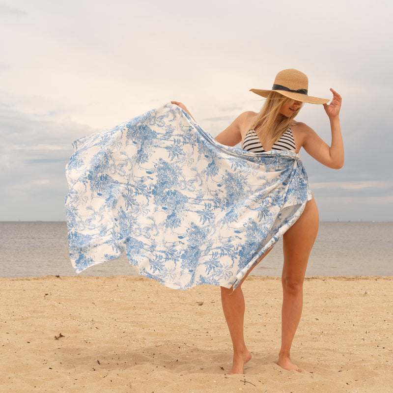 Woman on a beach holding a blue and white floral towel