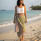 Woman on a beach wearing a colorful sarong over a white top
