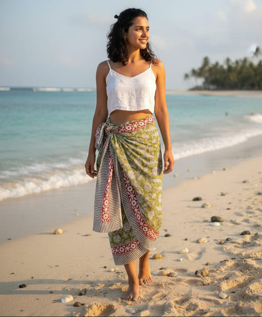 Woman on a beach wearing a colorful sarong over a white top